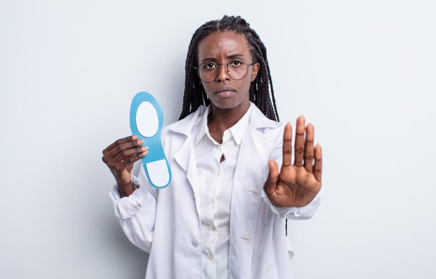 Pretty black woman looking serious showing open palm making stop gesture. podiatrist concept