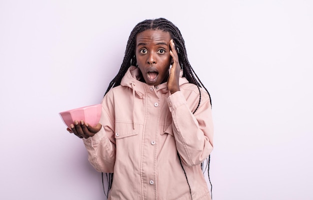 Pretty black woman looking surprised, realizing a new thought, idea or concept. empty bowl concept