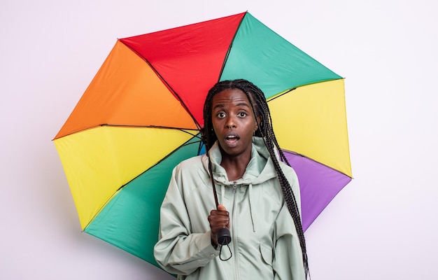 매우 충격을 받거나 놀란 우산 개념을 찾고 있는 예쁜 흑인 여성