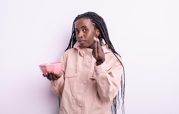 Pretty black woman making capice or money gesture, telling you to pay. empty bowl concept