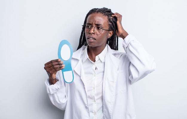 Pretty black woman smiling happily and daydreaming or doubting. podiatrist concept