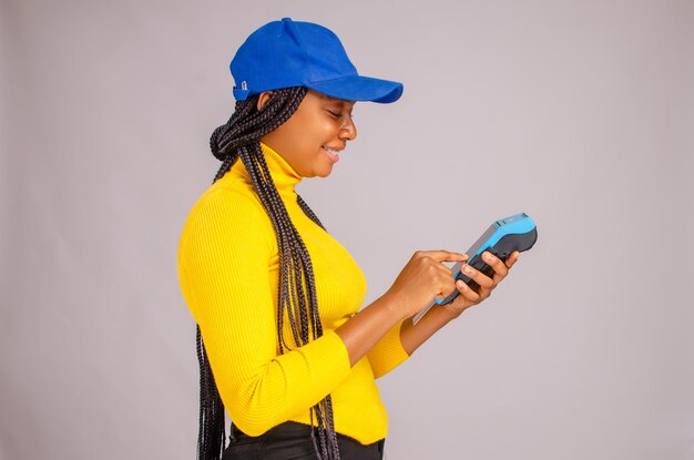 Pretty black woman smiling while holding and showing a point of sale device