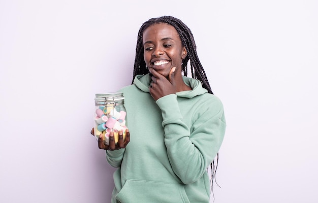 Pretty black woman smiling with a happy, confident expression with hand on chin. jelly candies concept