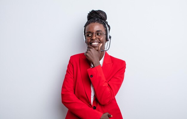 pretty black woman smiling with a happy, confident expression with hand on chin. telemarketing concept