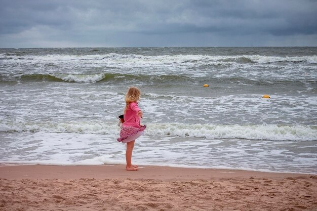 Pretty blond girl on the bank of the rough seas