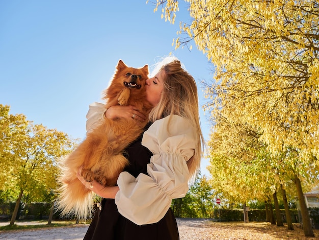 Pretty blond girl play with Pomeranian dog