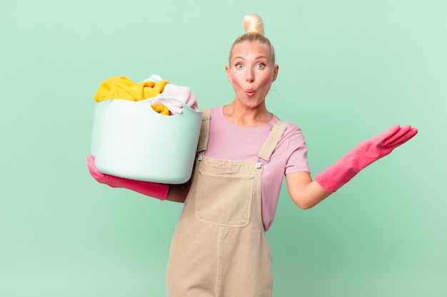 Pretty blond woman amazed, shocked and astonished with an unbelievable surprise washing clothes concept