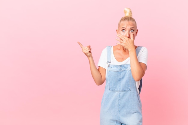 Pretty blond woman covering mouth with hands with a shocked