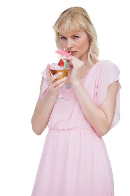 Pretty blond woman drinking cocktail and looking at camera