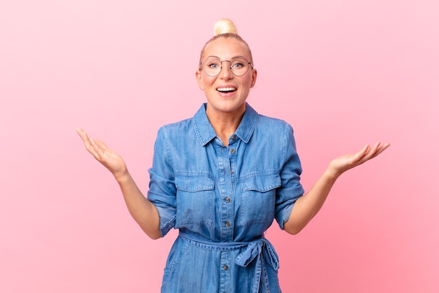 Pretty blond woman feeling happy and astonished at something unbelievable