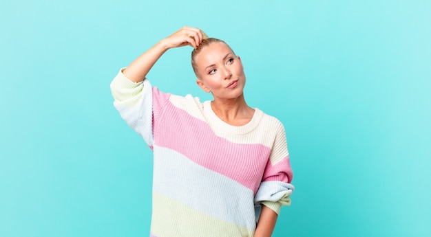 Pretty blond woman feeling puzzled and confused, scratching head