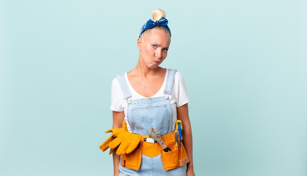 Pretty blond woman feeling sad, upset or angry and looking to the side and repairing house concept