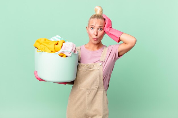 pretty blond woman feeling stressed, anxious or scared, with hands on head washing clothes concept