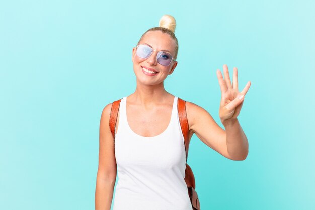 pretty blond woman smiling and looking friendly, showing number four. summer concept