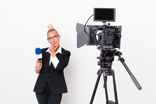 Donna abbastanza bionda che pensa dubbiosa e confusa e tiene in mano un concetto di presentatore pmicrophone