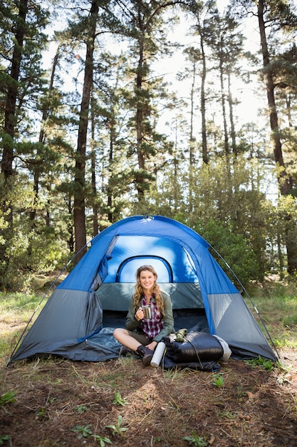 Foto camper abbastanza biondo che sorride e che si siede in tenda