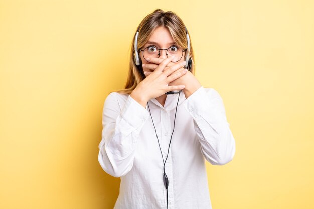 Pretty blonde girl covering mouth with hands with a shocked headset concept