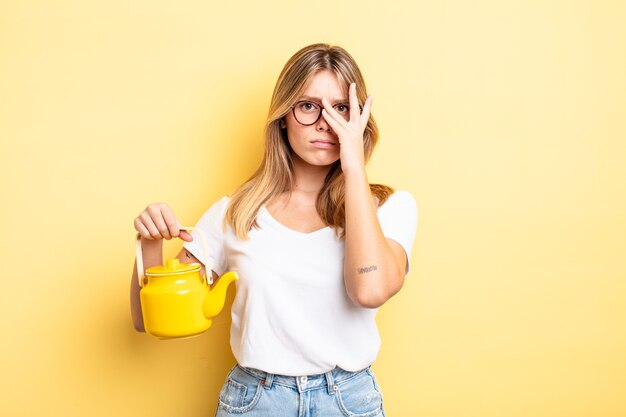 Pretty blonde girl feeling bored, frustrated and sleepy after a tiresome. teapot concept