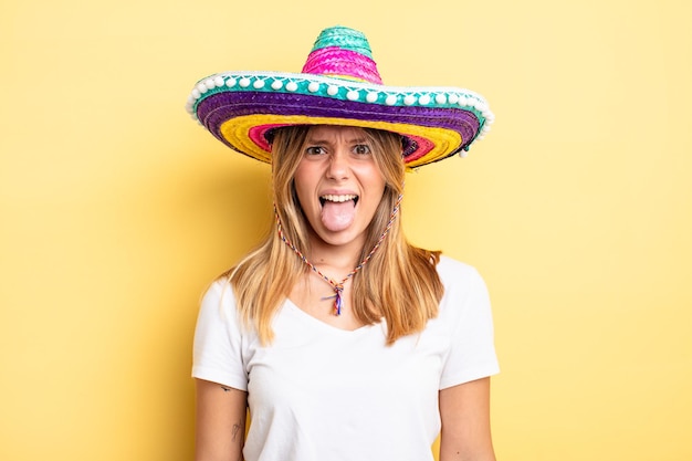 Pretty blonde girl feeling disgusted and irritated and tongue out. mexican hat concept