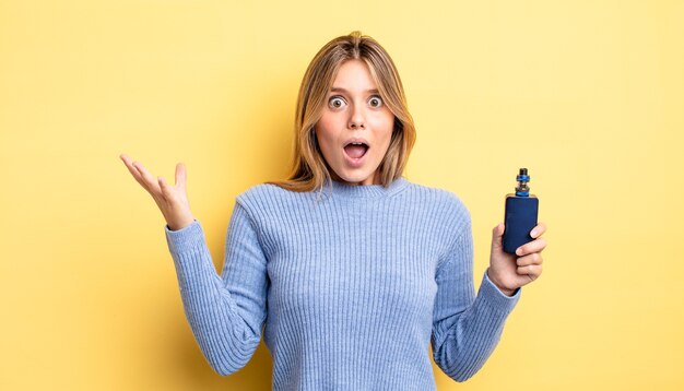 Pretty blonde girl feeling extremely shocked and surprised. smoke vaporizer concept