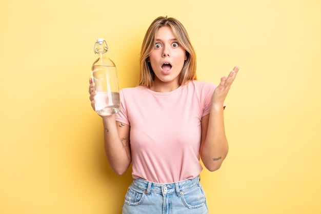 Pretty blonde girl feeling happy and astonished at something unbelievable. water bottle concept