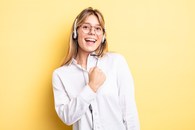 Pretty blonde girl feeling happy and facing a challenge or celebrating. headset concept