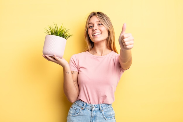 Pretty blonde girl feeling proud,smiling positively with thumbs up. houseplant concept