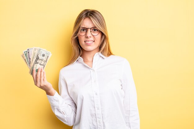 pretty blonde girl feeling puzzled and confused. dollar banknotes concept