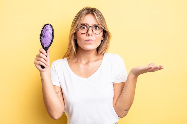 Pretty blonde girl feeling puzzled and confused and doubting. hair brush concept