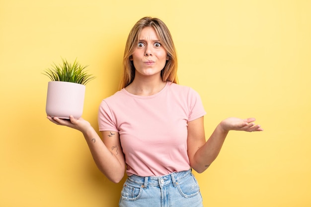 Pretty blonde girl feeling puzzled and confused and doubting. houseplant concept