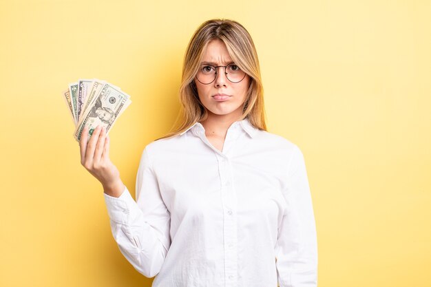 Pretty blonde girl feeling sad and whiney with an unhappy look and crying. dollar banknotes concept