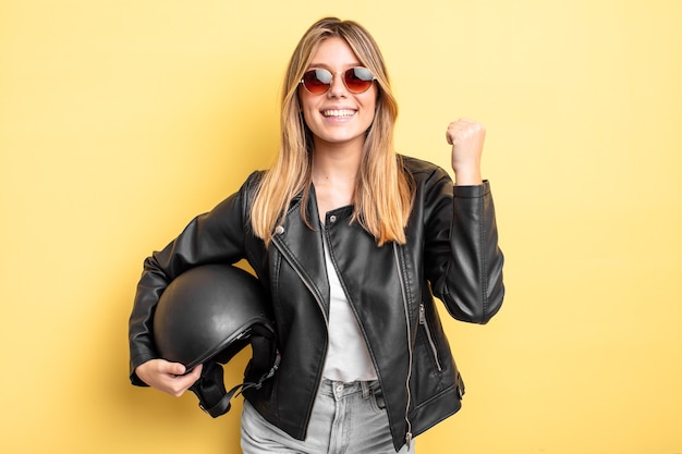 Pretty blonde girl feeling shocked,laughing and celebrating success. motorbike helmet concept
