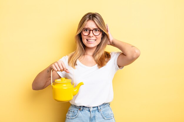 Pretty blonde girl feeling stressed, anxious or scared, with hands on head. teapot concept