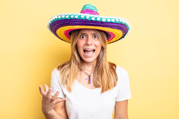 Foto bella ragazza bionda che sembra arrabbiata, infastidita e frustrata, concetto di cappello messicano