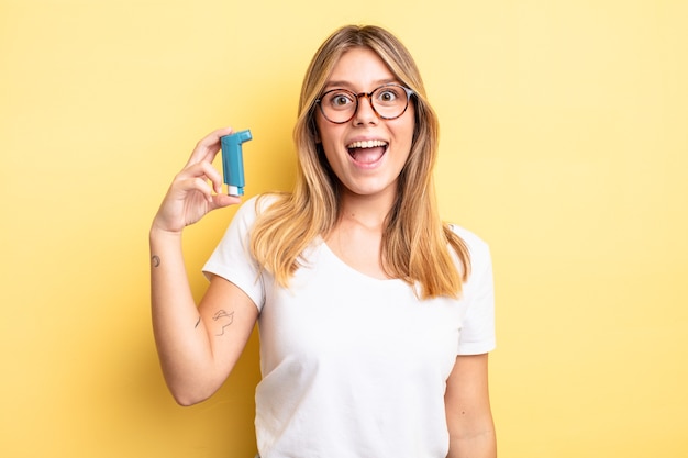 Pretty blonde girl looking happy and pleasantly surprised. asthma inhaler concept