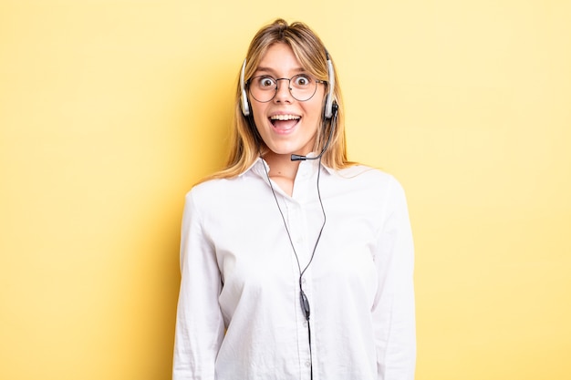 Bella ragazza bionda che sembra felice e piacevolmente sorpresa. concetto di auricolare