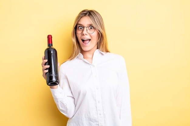 Pretty blonde girl looking happy and pleasantly surprised. wine bottle concept