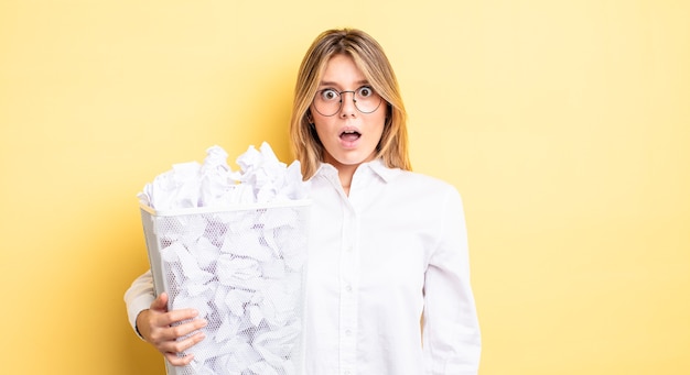 Pretty blonde girl looking very shocked or surprised. paper balls trash concept