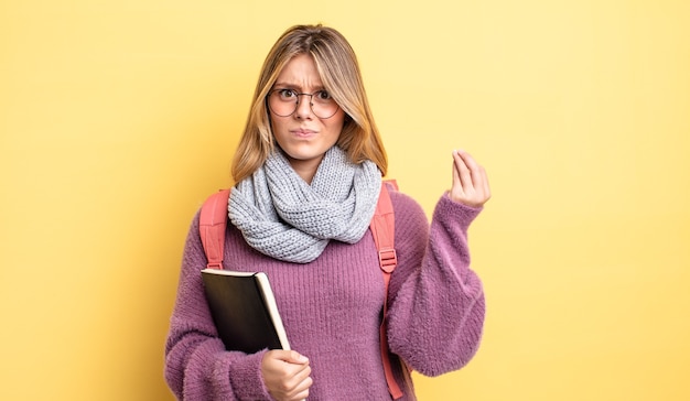 pretty blonde girl making capice or money gesture, telling you to pay. student concept