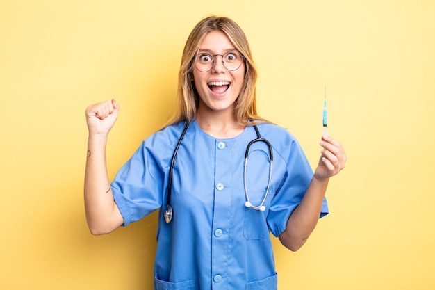 Pretty blonde girl shouting aggressively with an angry expression. nurse an vaccine concept