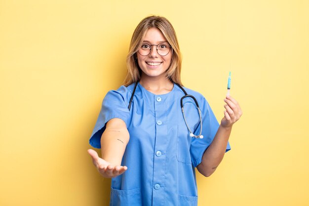 Bella ragazza bionda sorridente felicemente con amichevole e offrendo e mostrando un concetto. nutrire un concetto di vaccino