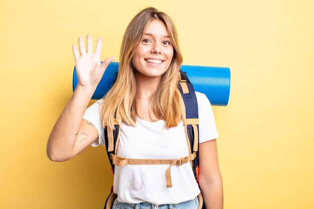 Pretty blonde girl smiling and looking friendly, showing number five.  hiker concept