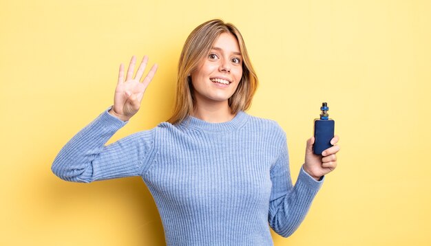 Pretty blonde girl smiling and looking friendly, showing number four. smoke vaporizer concept