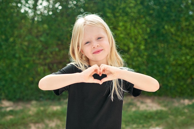 写真 緑の壁の前に立っているかなりブロンドの女の子黒の t シャツをモックアップします。