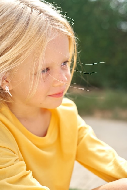 Photo pretty blonde girl yellow t shirt sitting before green wall top view