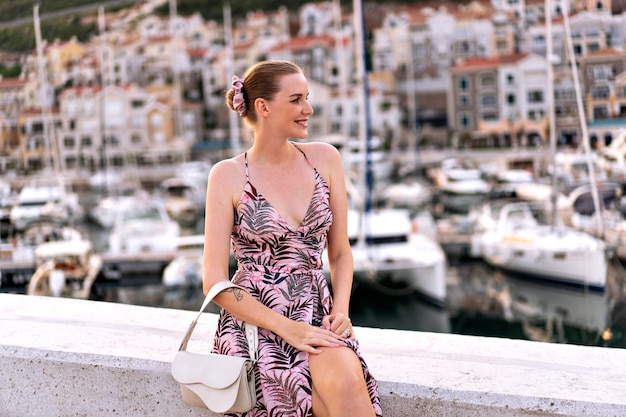 Foto bella donna bionda glamour che invia un bacio d'aria vicino al porto turistico del montenegro