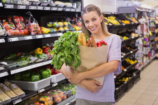 Pretty blonde holding bag with bread and vegetable 