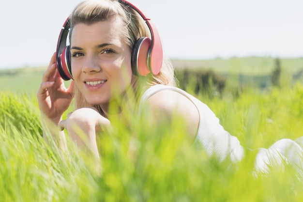 Foto bella bionda sdraiata sull'erba ascoltando musica