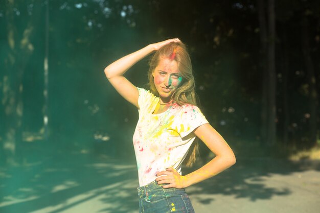 Photo pretty blonde model playing with green dry paint holi in the park