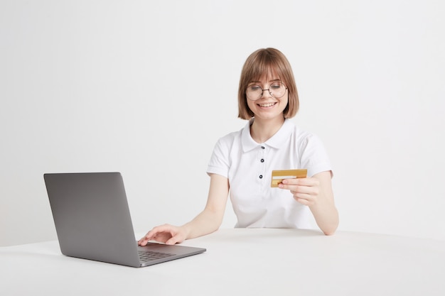 Pretty blonde pays for purchases online on a laptop, in an online store, sitting at home. Payment is made by credit card